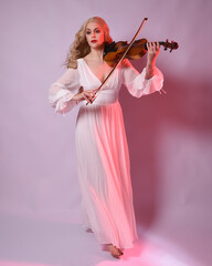 Full length portrait of beautiful blonde model wearing elegant white halloween gown, historical...