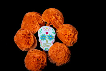 Cookies with shapes of Mexican catrinas and orange marigold flowers to celebrate Halloween or Day of the Dead on black background
