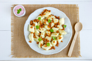 Kluski leniwe z bułką tartą smażoną na maśle i z cynamonem posypane listkami mięty.