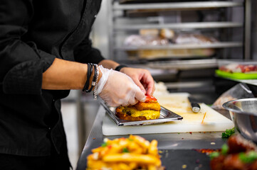 chef hand cooking burger with vegetables and meat on restaurant kitchen