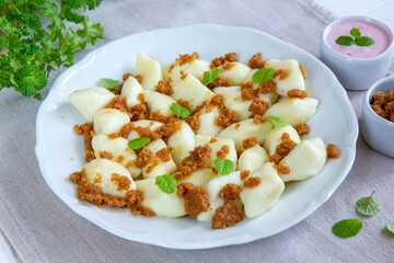 Kluski leniwe z bułką tartą smażoną na maśle i z cynamonem posypane listkami mięty.