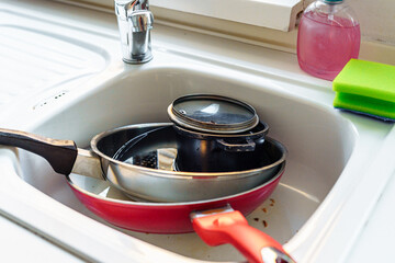 Pile dirty unwashed dishes in kitchen sink