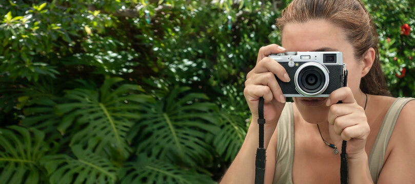 A woman taking pictures with a vintage camera outdoors. Traveling and photographing concept.