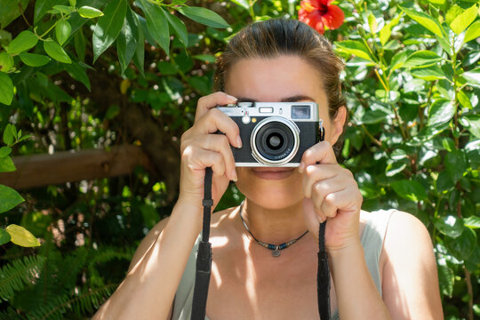 Young woman taking pictures with a compact camera outdoors. Traveling and photographing concept.