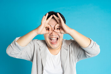 Portrait of an Asian guy posing on a blue background