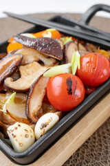 Fried shiitake mushrooms with vegetables, bell peppers, onions and tomatoes are ready for consumption. Vegetable vegetarian dish with shiitake mushrooms. National Asian cuisine