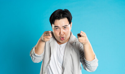 Naklejka premium Portrait of an Asian guy posing on a blue background