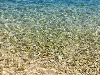 transparent turquoise sea water background with pebbles and rocks