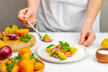 A woman is preparing a tomato salad. Ripe vegetables, herbs, aromatic spices, olive oil