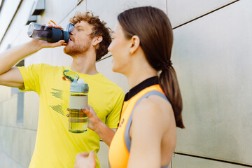 Athletic couple drinking water after workout outdoors