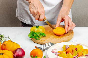 A woman is preparing a tomato salad. Ripe vegetables, herbs, aromatic spices, olive oil