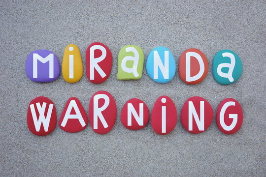 Miranda Warning, police notification text composed with hand painted multi colored stone letters over green sand