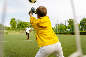 Kid catching ball while playing football with african man on a field