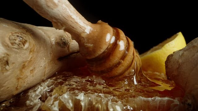 On a black background, there are honeycombs with honey, ginger, and lemon. The camera zooms out, and I place a wooden honey spoon on top. Macro