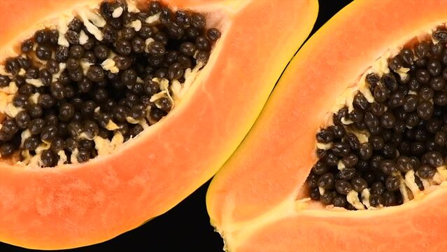 Papaya fruits isolated on black background. Halved fresh organic Papaya exotic fruit design, close up. Top view, rotating, slow motion