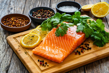 Fresh raw salmon steak with salt and fresh vegetables on wooden background