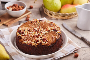 Chocolate sponge cake with pears and hazelnuts. Delicious autumn homemade sweet pie with seasonal...
