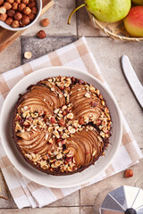 Chocolate sponge cake with pears and hazelnuts. Delicious autumn homemade sweet pie with seasonal fruits. Top view.