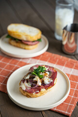 a prosciutto batard bread sandwich with mushroom, sauteed onion, arugula and burnt cheese