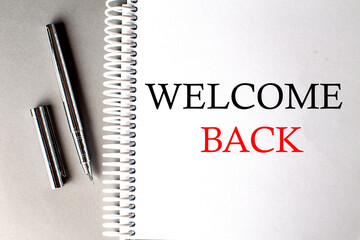 WELCOME BACK text on a notebook with pen on grey background