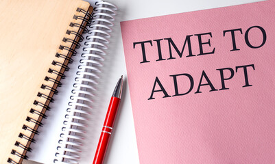 TIME TO ADAPT word on the pink paper with office tools on white background