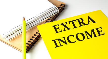 EXTRA INCOME text written on a yellow paper with notebook