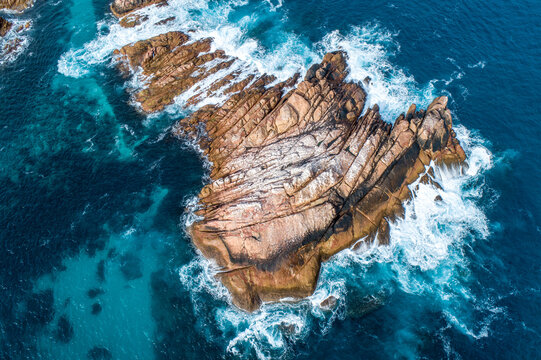 Waves crash against rugged coastal rocks - Powered by Adobe