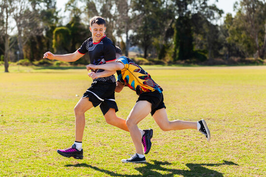 Aboriginal football players running on sports ground field tackling during game