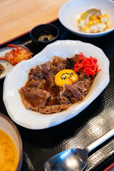 a Japanese set menu, consists of miso soup, soft boiled egg, vegetables, fruits and beef strips with sweet soy sauce also called as gyudon