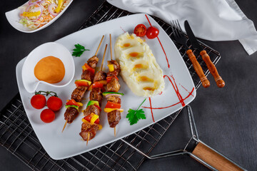 Presentation of grilled pork skewer with boiled potato on wooden table was impressive.