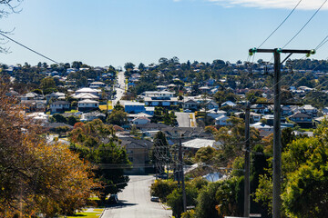 Looking down road in the city of Newcastle with power poles and lines going to houses