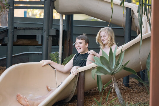 Brothers riding water slide together on holiday at caravan park