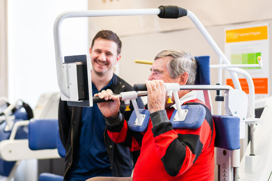 physiotherapist chatting with client using exercise therapy equipment