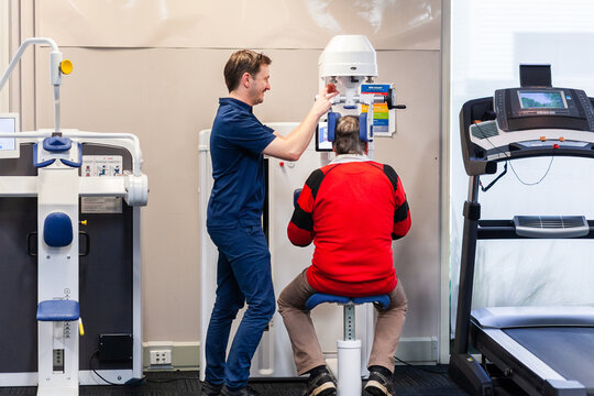 physiotherapist smiling and adjusting exercise therapy equipment for client