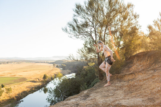 First nations australian teen doing a storytelling dance pose on cliff
