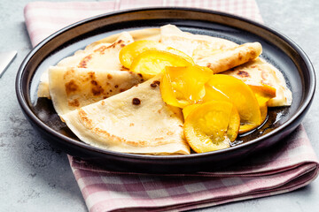 Plate of crepes with orange on gray background