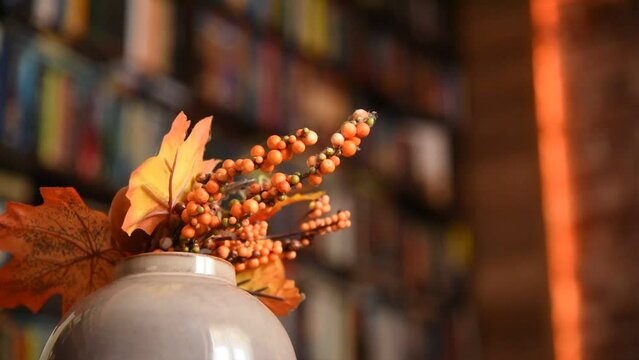 Rotating autumn leaves and dry flowers decoration in a library full of books