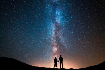 Fantasy landscape, couple in love standing on the hill, and looking at the Milky Way galaxy . - obrazy, fototapety, plakaty