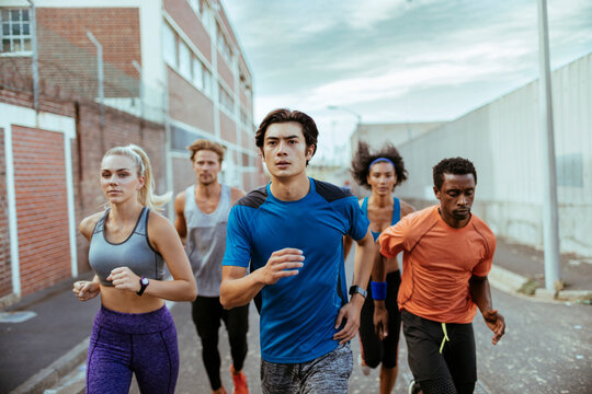 Young and diverse group of friends jogging and running together in the city