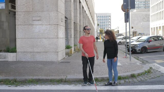 solidarity, handicap - blind man accepts the help of a young woman to cross 