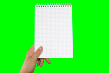 Female Hand Holding Notepad with blank Page Isolated On Green Background. Close Up. Chroma Key Screen. Woman's Hand with Empty Card Paper MockUp. Advertisement gesture. Notebook Mock Up. Greenscreen
