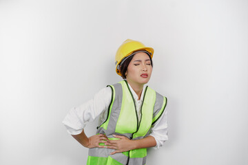 Asian woman labor worker wearing a safety helmet and vest hold hand on stomach suffers pain...