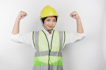 A portrait of Asian woman labor wears safety helmet and vest, showing strong gesture by lifting her arms and muscles smiling proudly. Labor's day concept.