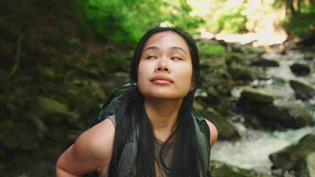 Happy asian tourist woman looking around near mountain river in woods