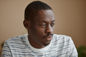 Closeup portrait of adult African American man looking away with sadness and suffering from mental health issues and depression