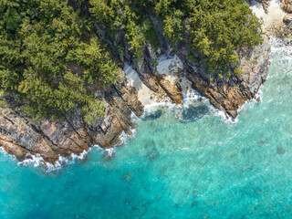 Fototapeta premium High angle aerial bird's eye drone view of the rocky coastline and tiny beaches on Arkhurst Island, a small islet near Hayman Island, Whitsunday Islands, Great Barrier Reef, Queensland, Australia.