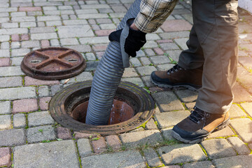 worker holding pipe and pumping out household septic tank. drain and sewage cleaning service