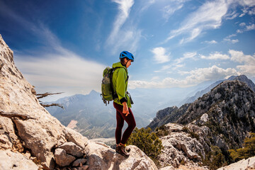 Obraz premium A girl with a backpack on a hike. adventure in the mountains. hiking with a backpack. girl with a backpack in the high mountains. Rock climbing and mountaineering concept.