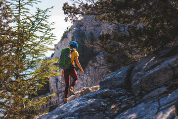 climber goes along the rocky ridge. girl climbing in the mountains. the concept of adventure and hiking in the mountains.