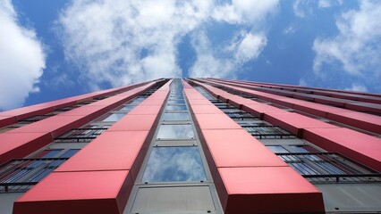 Hochhaus mit roter Fassade und Fensterfront in urbaner Umgebung